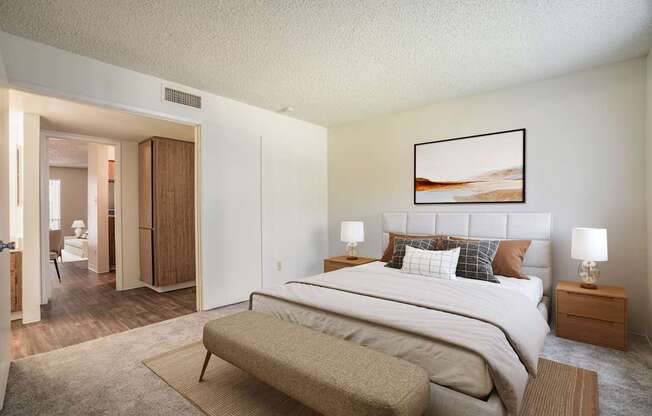 A bedroom with a large bed and a painting on the wall.