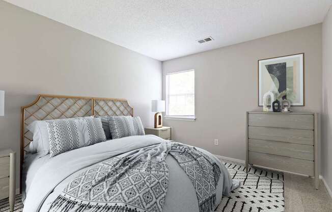 A bedroom with a bed, nightstand, and a dresser.
