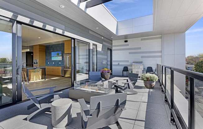 A modern balcony with grey furniture and a glass door leading to a living room.