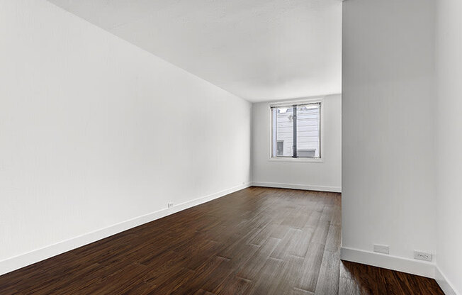 a bedroom with hardwood floors and a window