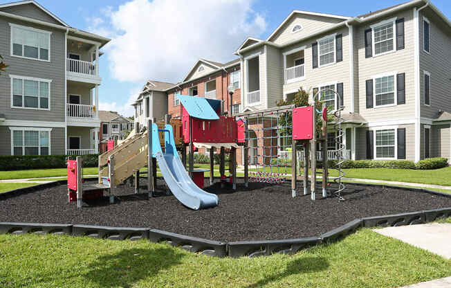 an outdoor playground in front of an apartment building at Volare at the Woodlands, The Woodlands, TX, 77384