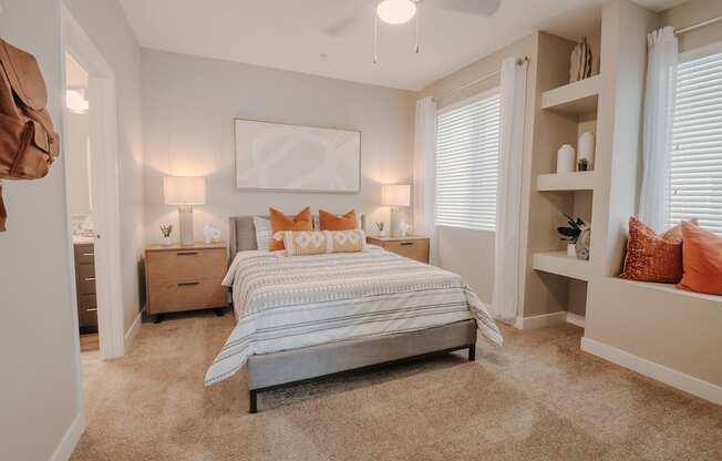 Spacious one bedroom with built-in shelving, window seat, decorated with two night stands, a bed, and artwork.