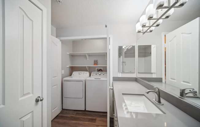 a white laundry room with a sink and a washer and dryer in it