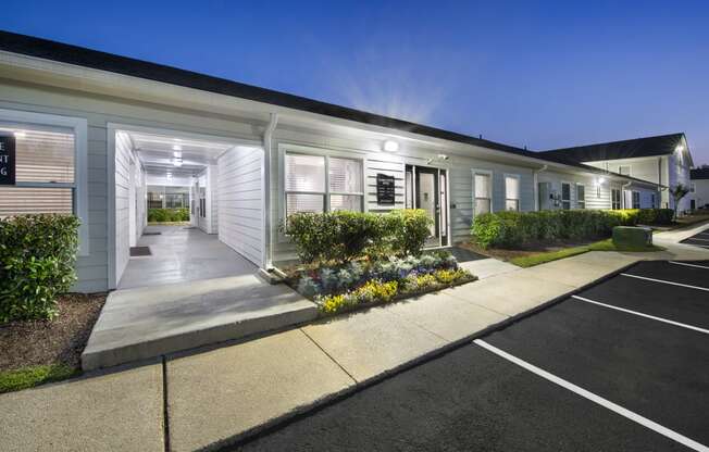 the exterior of a white building with a driveway and landscaping