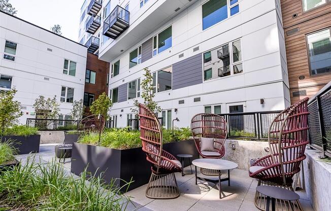 a patio with chairs and a table in front of an apartment building