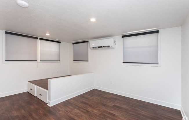 a living room with white walls and wood flooring and a window