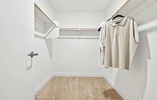 a spacious walk in closet with a white wall and a white closet door with a