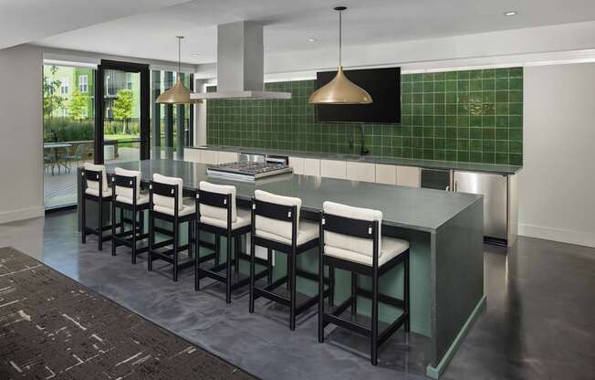 A kitchen with a green tiled backsplash and a long island with chairs.