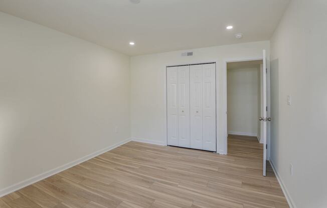 A room with a white door and wooden flooring.