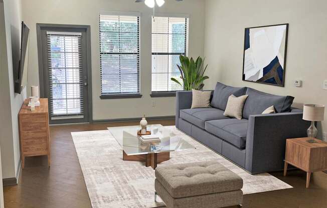 A living room with a grey couch, a coffee table, and a ceiling fan.