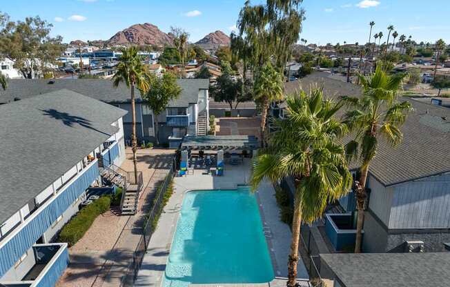 A pool surrounded by palm trees and a mountain in the distance.
