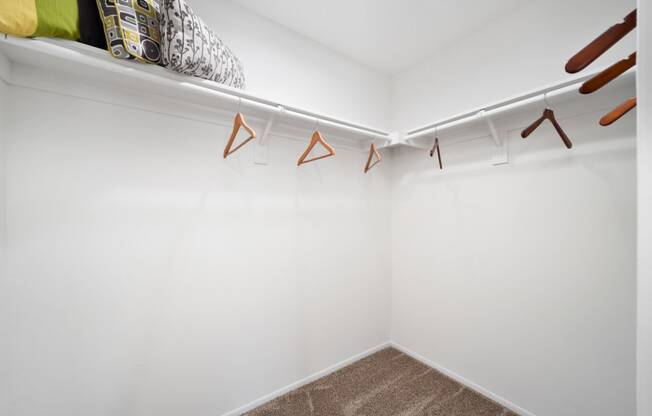 a walk in closet with white walls and a white shelf