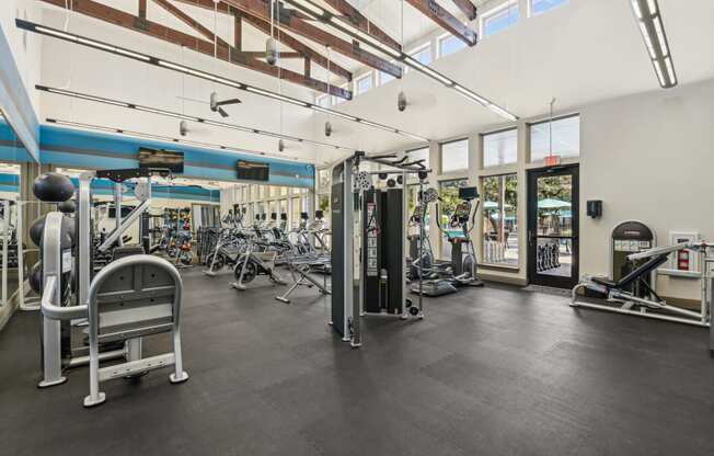 a gym with weights and cardio equipment and windows