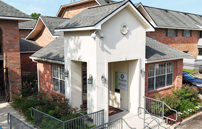 A small white building with a black roof and a sign that reads "21 SOUTH" is surrounded by a metal fence.