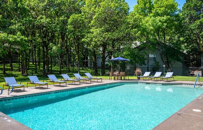 the pool is surrounded by lawn chairs and trees