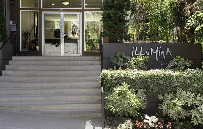 the entrance to the property building with a staircase and plants at Illumina Apartment Homes, Washington