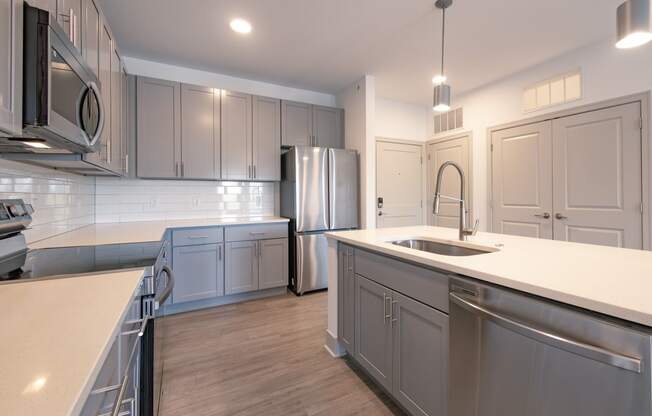 an open kitchen with stainless steel appliances and white counter tops