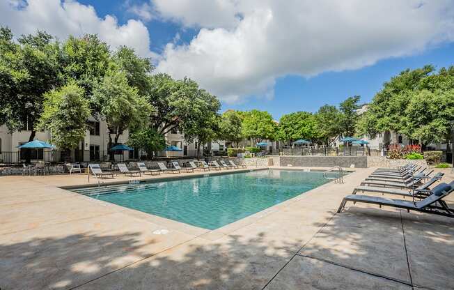 a resort style pool with lounge chairs and trees