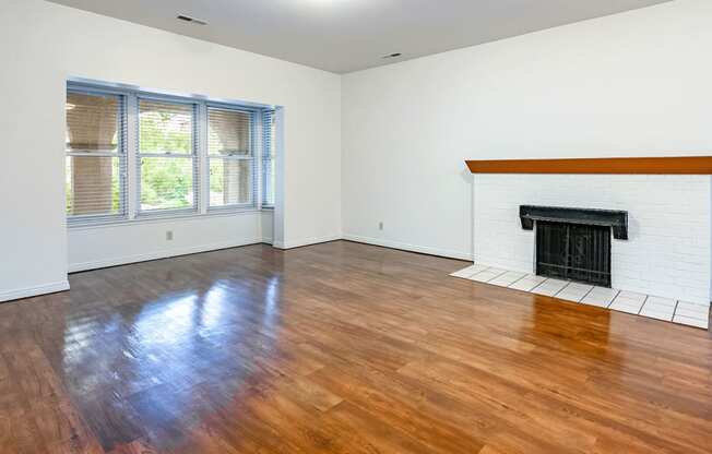 Living room with fireplace, windows, and hardwood flooring