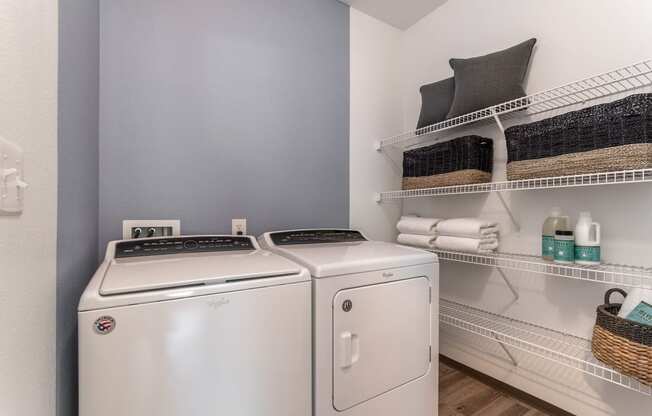a laundry room with a washer and dryer and a shelf with towels