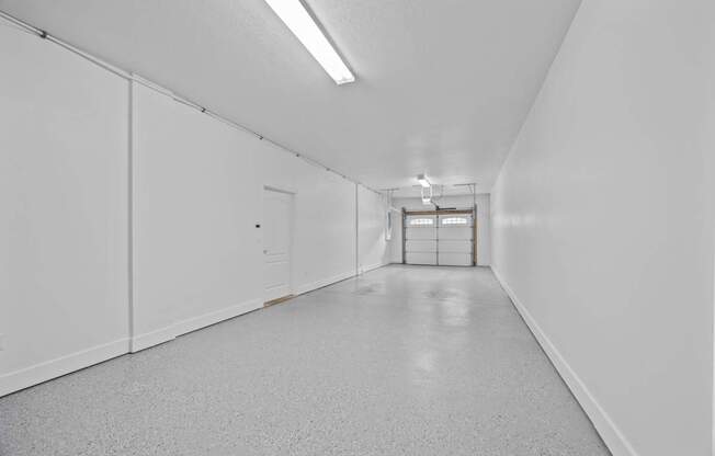 A long white hallway with a door at the end.