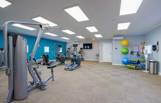 A gym with a variety of equipment and a TV on the wall.