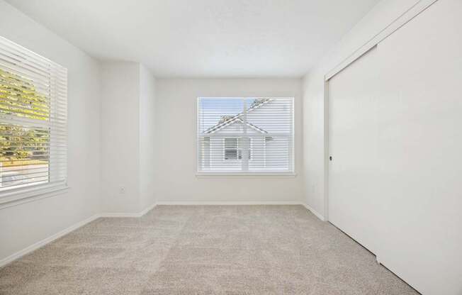 A room with a carpeted floor and a window with blinds.
