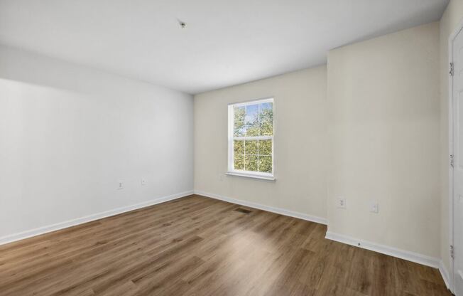 a room with white walls and a window and wooden floors