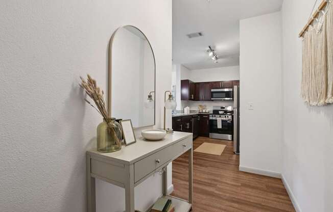 A vanity table with a mirror and a vase with dried flowers on it.