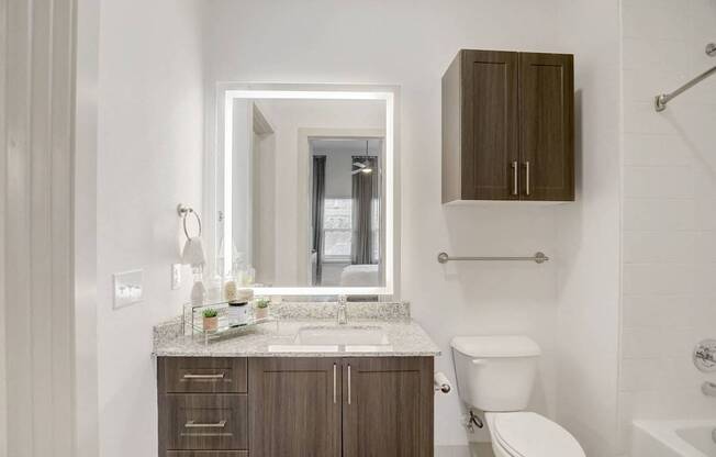 A bathroom with a white toilet, sink, and mirror at Infinity on the Point Apartments, Texas