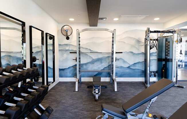 A gym with a wall mural of mountains and a row of treadmills.
