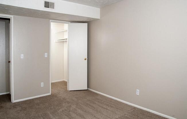 an empty room with a carpeted floor and a closet