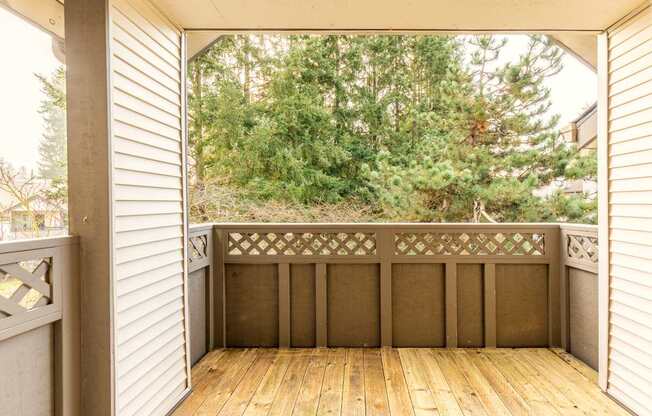 A wooden deck with a railing and trees in the background.