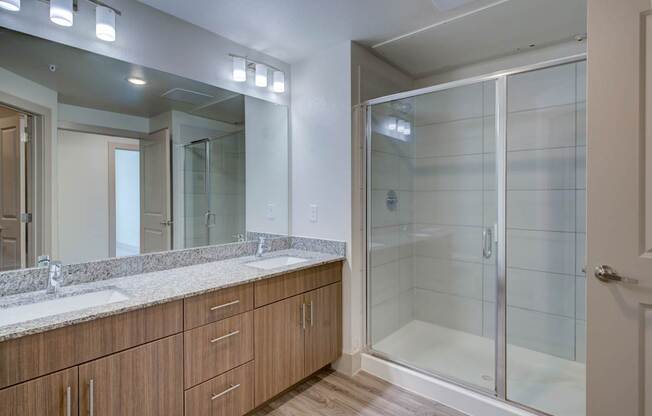 A bathroom with a walk-in shower and double sinks.