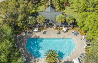 A large swimming pool surrounded by trees and a house in the background.