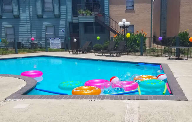 A pool with a floats and noodles and beach balls