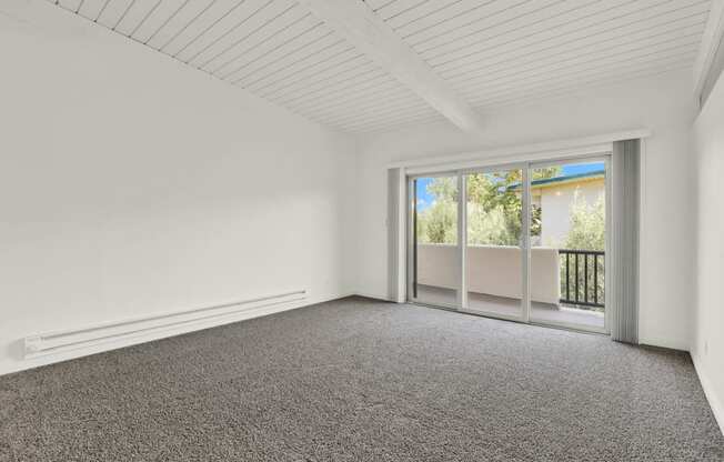 an empty living room with carpet and a sliding glass door at Willow Tree Apartments, Torrance