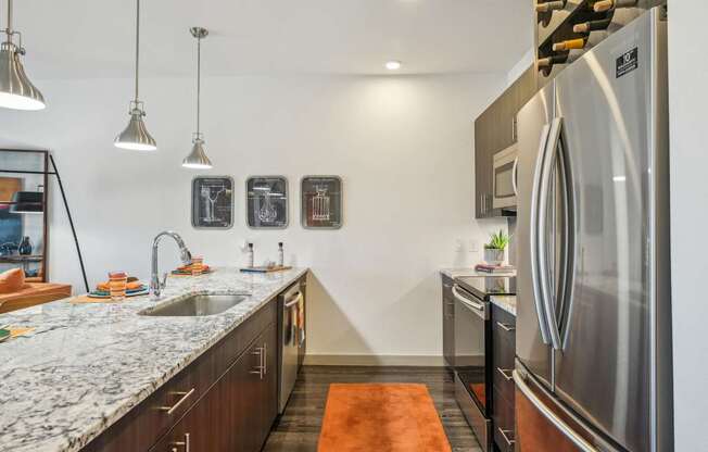 A modern kitchen with a marble countertop and stainless steel appliances.