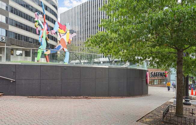 A large sculpture of a person made of colorful materials stands in front of a black wall.