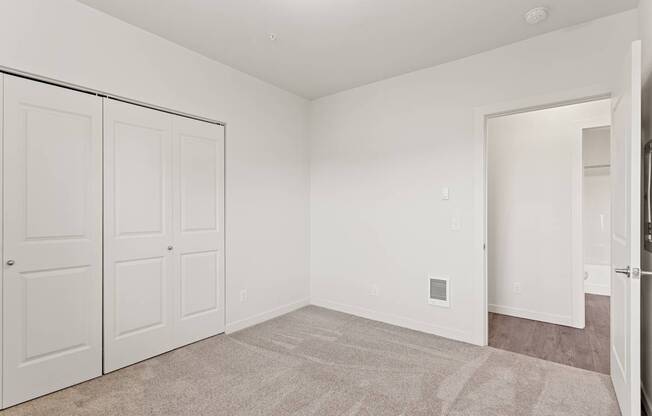 A white room with a carpeted floor and two white doors.