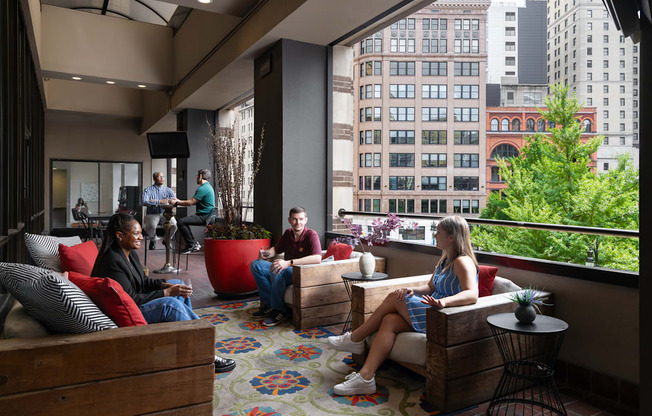 people sit on couches and chairs in a lobby with a large window