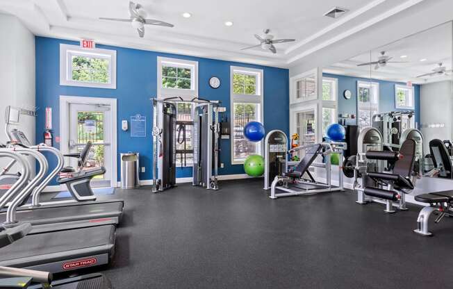 a gym with cardio equipment and weights in a building with blue walls