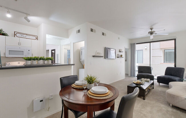 an apartment living room with a dining table and a kitchen in the background