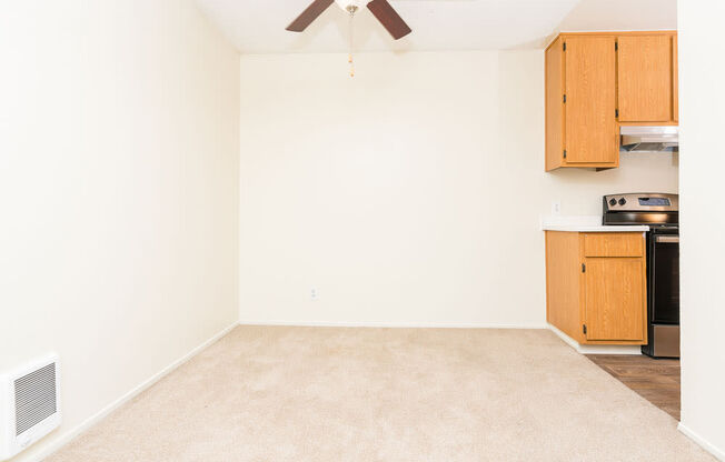 an empty living room with a ceiling fan and