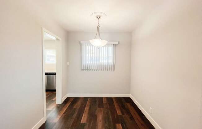 an empty living room with hard wood flooring and a window