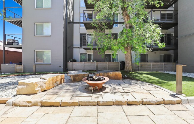 a fire pit in the middle of a grassy area with an apartment building in the background