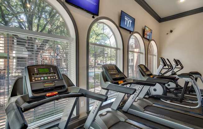 A gym with treadmills and a TV mounted on the wall.