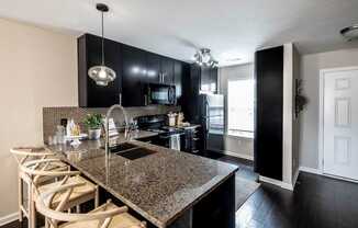 A kitchen with black cabinets and granite countertops.