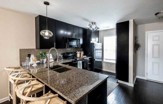 A kitchen with black cabinets and granite countertops.