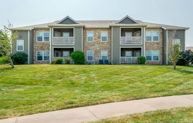 an apartment building with a lawn and a sidewalk in front of it